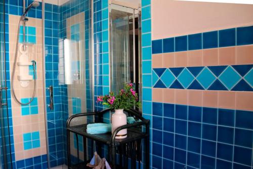 a blue tiled bathroom with a vase of flowers on a table at SARDINIA RE - Casa Cipro in Castelsardo