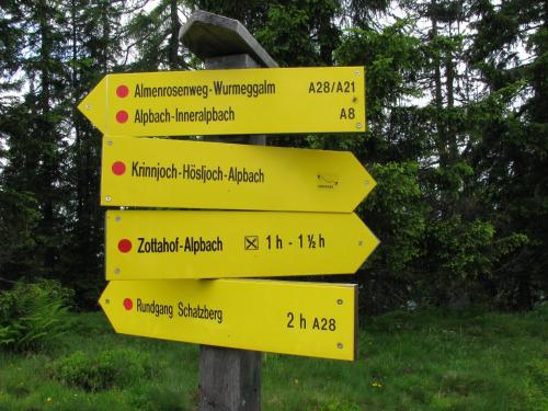 a yellow street sign with arrows pointing in different directions at Bergwald Appartements Alpbach in Alpbach