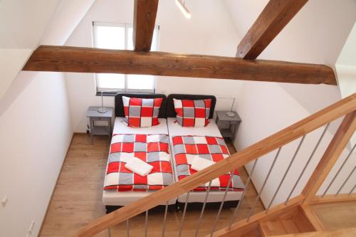 Zimmer im Dachgeschoss mit einem Bett mit roten und weißen Kissen in der Unterkunft Schwaben Apartment in Oberboihingen