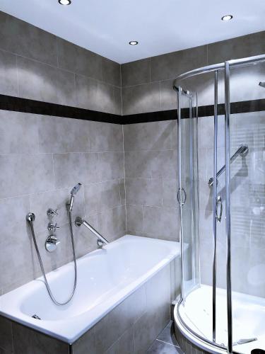 a bathroom with a shower and a bath tub at Hotel Sylter Blaumuschel in Westerland (Sylt)