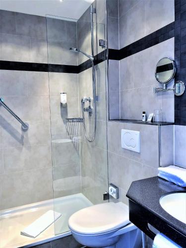 a bathroom with a shower and a toilet and a sink at Hotel Sylter Blaumuschel in Westerland (Sylt)
