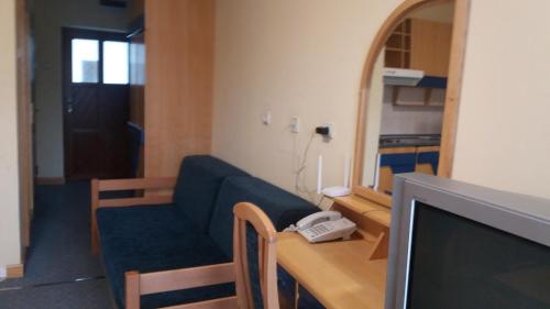 a living room with a blue couch and a television at Garni Lupus prenoćište in Kanjiža