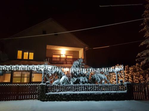 a house covered in christmas lights in the snow at Oázis Vendégház és Appartman in Szilvásvárad