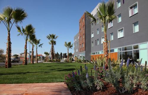 a park with palm trees and a building at Cosmopolitan Hotel in Civitanova Marche