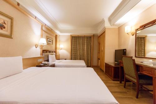 a hotel room with two beds and a desk and a television at SL MOTEL in Zhonghe