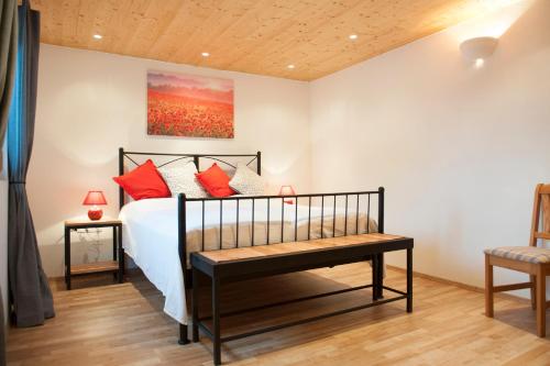 1 dormitorio con cama con almohadas rojas y banco en "Domaine de la Mance" - Gite-Maison de vacances, en Vitrey