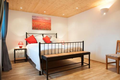 a bedroom with a bed with red pillows and a bench at "Domaine de la Mance" - Grand gîte avec bain nordique in Vitrey-sur-Mance