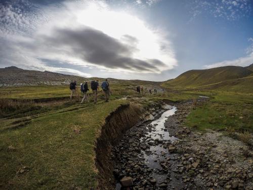 a group of people walking down a hill next to a stream at Gaia Guesthouse in Dilofo