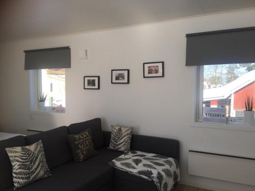a living room with a black couch and two windows at Great Stay Guest House Sandviken in Sandviken