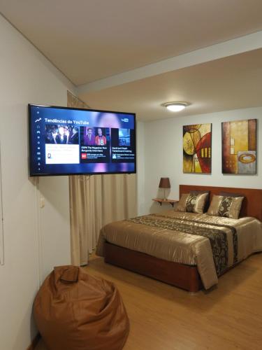 ポンタ・デルガダにあるCenter City Garden Apartmentのベッドルーム1室(ベッド1台、壁に大型テレビ付)