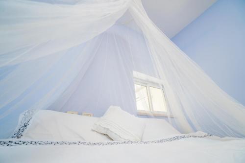 a bed with a white canopy and a window at Sweet Home in Arad