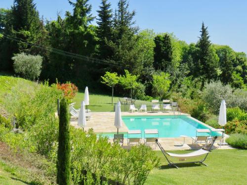 La Giravolta Country House في Barchi: مسبح في حديقة فيها كراسي ومظلات