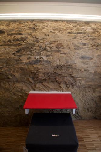 a red bench in front of a stone wall at B&B Mare di Fuori in Stintino