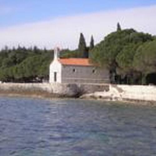 a church sitting on the shore of a body of water at Apartments & Rooms BARBARA in Umag