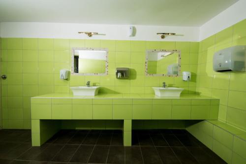 a green bathroom with two sinks and mirrors at Hotel Vlassis in Stómion