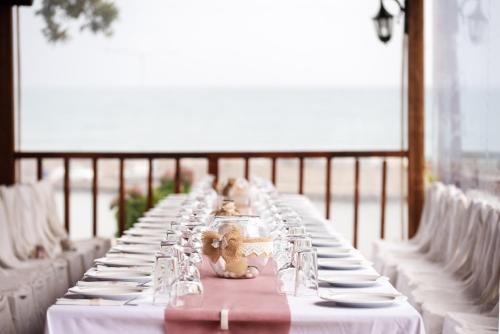 a long table with white plates and wine glasses at Hotel Vlassis in Stómion