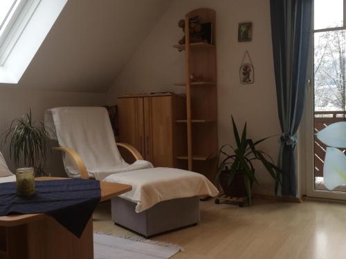 a living room with a white chair and a table at Ferienwohnungen Urbanitsch in Klöch