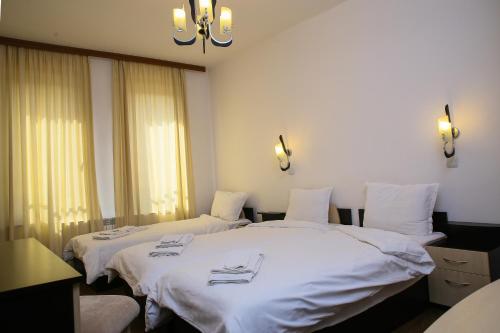 two beds in a room with white sheets at Hotel Zlatograd in Zlatograd