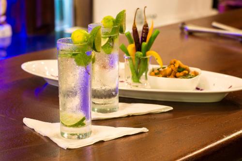 a table with two glasses of water and a plate of food at Okwin Resort in Kandy