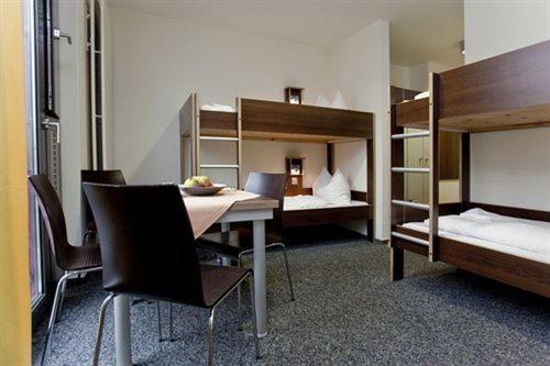 デュッセルドルフにあるユーゲンデルベルゲ デュッセルドルフのテーブル、椅子、二段ベッドが備わる客室です。
