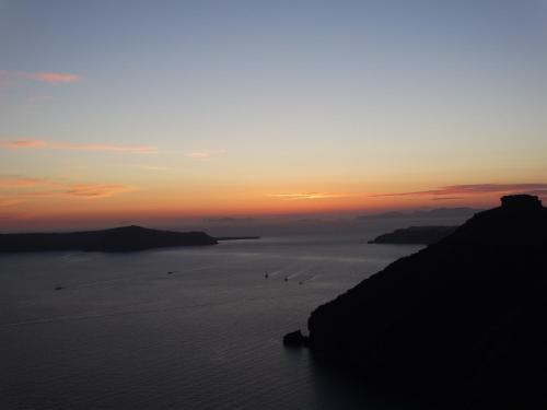 a group of birds in the water at sunset at Yposkafo Suites - Studio - Santorini in Fira
