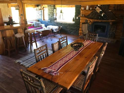 a wooden table and chairs in a room with a fireplace at Lodge Tikilen Caviahue in Caviahue