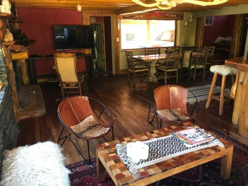 a living room with chairs and a table and a dining room at Lodge Tikilen Caviahue in Caviahue
