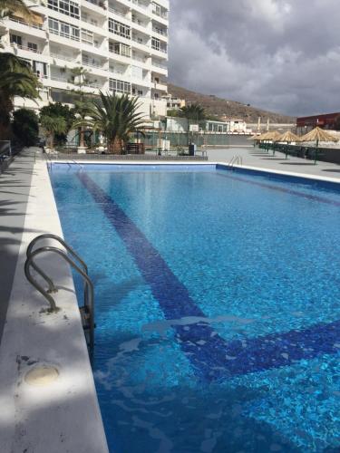 a large blue swimming pool in front of a building at Cozy Apartment in Candelaria