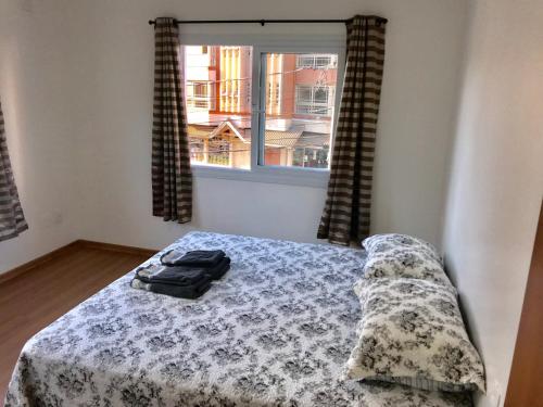 a bedroom with a bed and a window at Apartamento no Centro de Gramado in Gramado