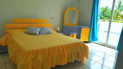 1 dormitorio con cama con colcha de color naranja y espejo en Résidence Le Dattier, 2 bedrooms apartment, Flic en Flac, en Flic en Flac