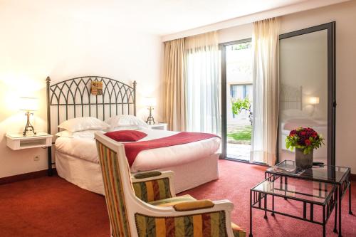 een slaapkamer met een groot bed en een tafel en stoelen bij Avignon Grand Hotel in Avignon