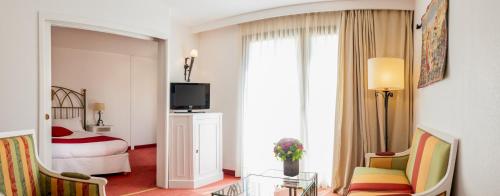 a hotel room with a bedroom with a bed and a television at Avignon Grand Hotel in Avignon