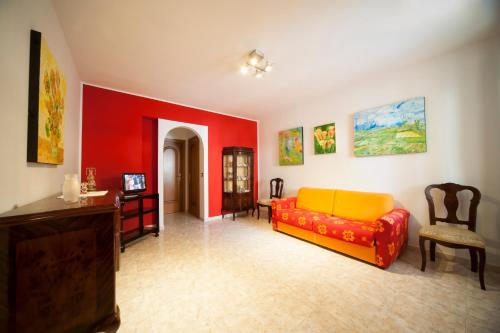a living room with a yellow couch and red walls at Colapesce Appartamento in Santa Teresa di Riva