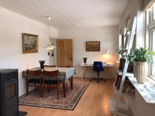a dining room with a table and a desk at Det lille røde hus in Nyord