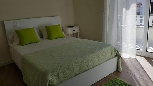 een slaapkamer met een bed met groene kussens en een raam bij GuestHouse O Cuco in Praia de Mira