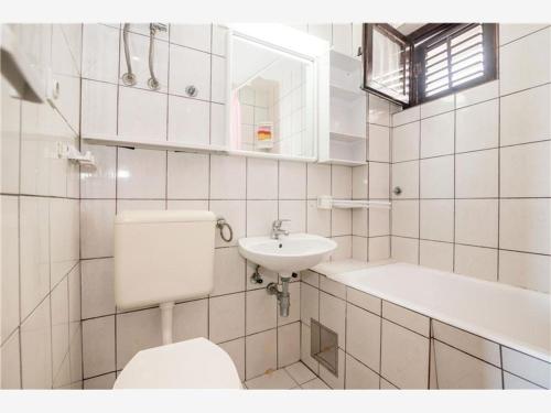 a white bathroom with a toilet and a sink at Apartments Maja in Drasnice