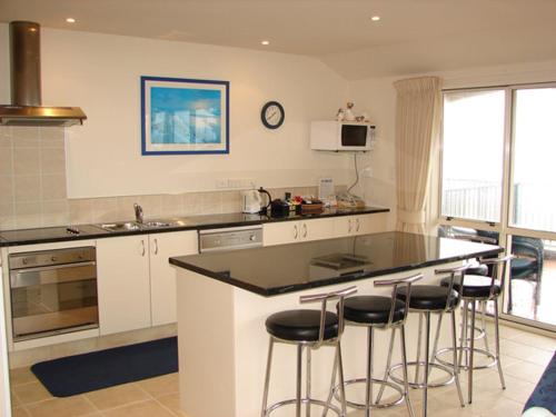 a kitchen with a counter top and bar stools at Pavilion Beachfront Apartments in Mount Maunganui