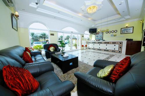 a living room with black leather couches and a television at Muscat International Hotel in Muscat