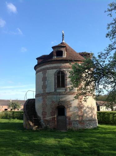 an old brick building in a field of grass at Le Rucher in Bois-Normand-près-Lyre