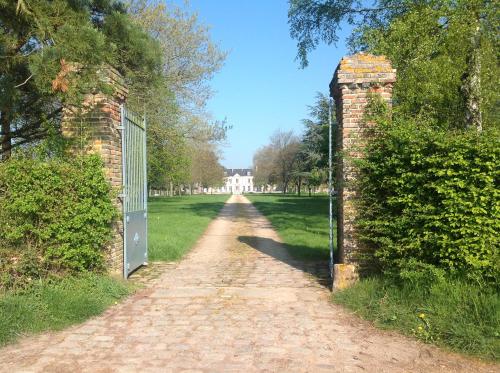 a gate on a brick wall next to a dirt road at Le Rucher in Bois-Normand-près-Lyre
