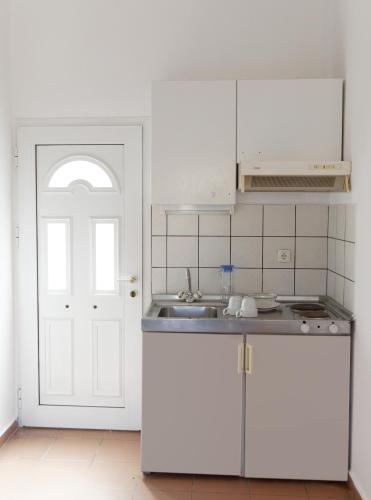 a kitchen with white cabinets and a white door at BLEU- VERT in Prinos