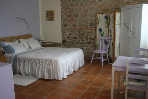 a bedroom with a bed and a chair at B&B La Fenice in Montegridolfo
