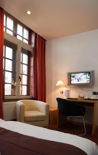 a hotel room with a bed and a desk and a chair at Hotel Bourgoensch Hof in Bruges