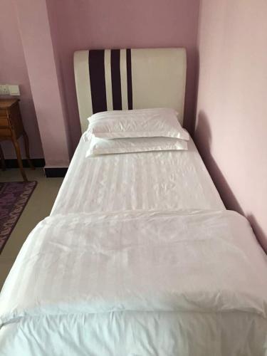 a bed in a room with a white bedsheet at Paka Tamim Seaview Hotel in Paka