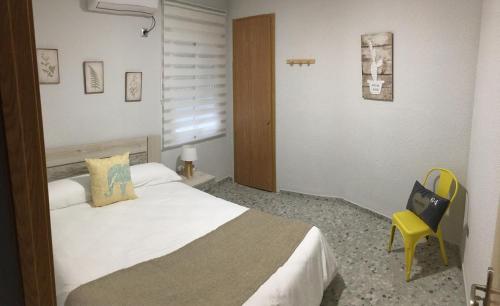コルドバにあるPiso plaza la compañíaのベッドと黄色い椅子が備わるホテルルームです。