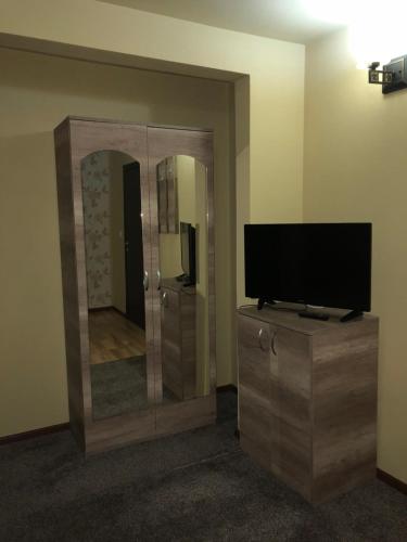 a living room with a tv and a mirror at Pensiunea Mirela Peștera Urșilor in Chişcău