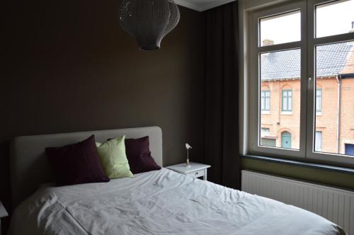 a bedroom with a white bed and a window at Vakantiehuis Jeanne Panne in Nieuwpoort