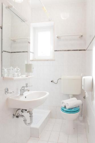 a white bathroom with a sink and a toilet at Hotel Krilo in Podstrana