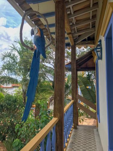 a blue parrot sitting on the porch of a house at Arraial Velho Pousada Tematica in Tiradentes