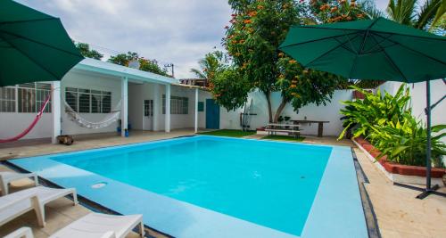 a swimming pool with two umbrellas next to a house at Casa Pancho Playa in San Francisco